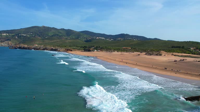 Flying backwards over the sea at Guincho beach , with waves breaking and Serra de Sintra in the background,Portugal