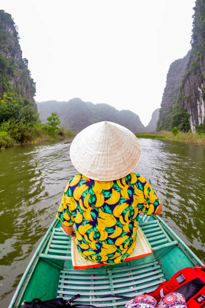 istock Tourist wearing a traditional vietnamese conical hat navigating Tam Coc river in Ninh Binh, Vietnam 2196571691