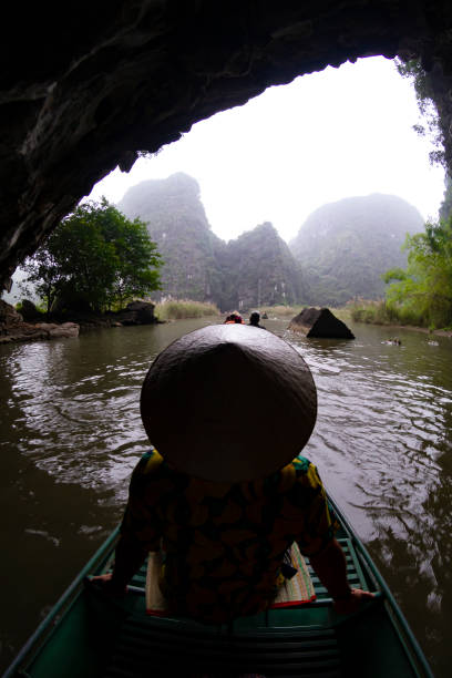 istock Tourist wearing a traditional vietnamese conical hat navigating Tam Coc river in Ninh Binh, Vietnam 2196571728