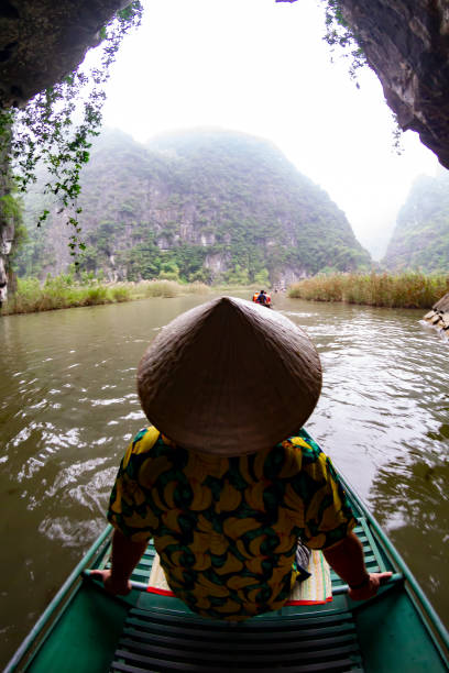 istock Tourist wearing a traditional vietnamese conical hat navigating Tam Coc river in Ninh Binh, Vietnam 2196571803