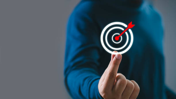istock Hand pointing at a digital target icon with a dart hitting the bullseye, symbolizing accuracy, precision, and goal achievement. 2196572229