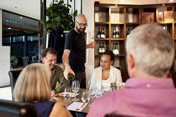 istock Bearded sommelier pouring white for wine tasting guests 2196574420