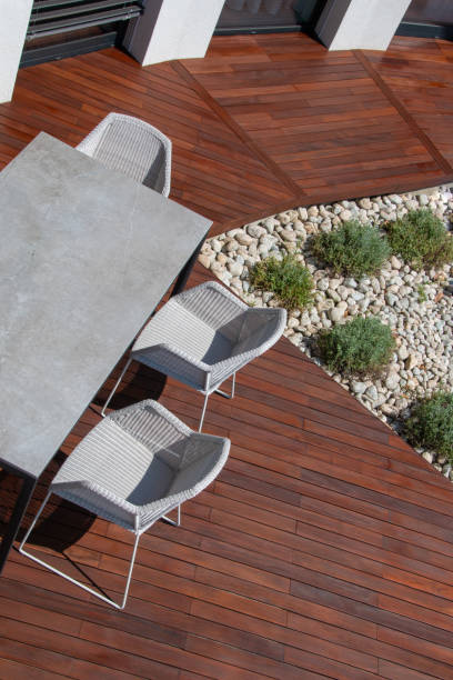 istock Contemporary outdoor dining area featuring concrete table and white rattan chairs on luxurious hardwood floor. High Angle shot 2196575920