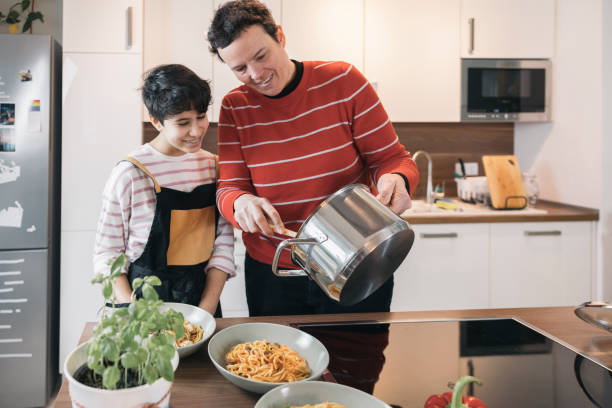 istock Mother pouring pasta into plates for lunch with her daughter in a modern kitchen 2196578451