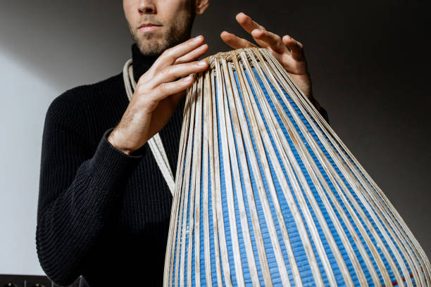 istock Close of man hands in black clothes, sitting and having joy while playing mridangam, an ancient percussion musical instrument originating from the Indian subcontinent in sunny day inside. Copy space 2196580914