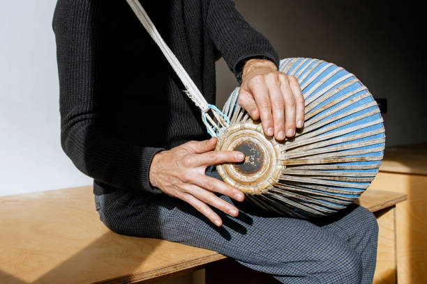 istock Close of man hands in black clothes, sitting and having joy while playing mridangam, an ancient percussion musical instrument originating from the Indian subcontinent in sunny day inside. Copy space 2196581301