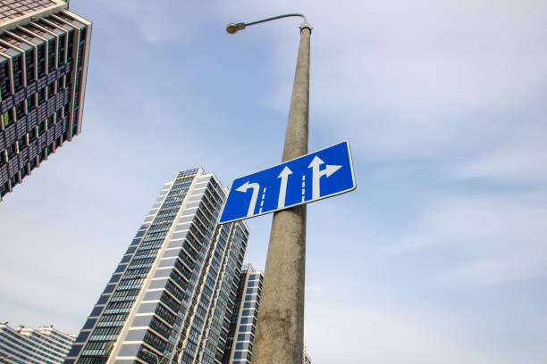 Road sign with arrows on city background close up