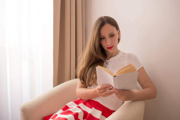 istock Woman reading a book in a cozy corner with natural light 2196582565
