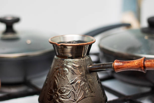 We make coffee on a gas stove. A woman hand puts a brass turk on the burner of a gas stove close-up.