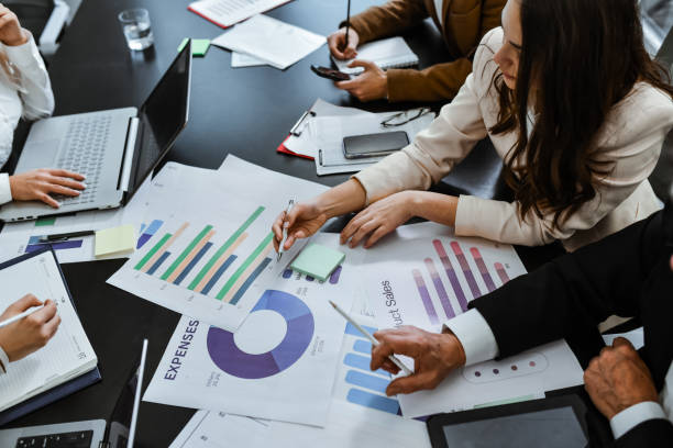 istock Employees Having Business Meeting Looking Through Graphs and Charts and Discussing 2196583976