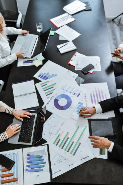 istock Employees Engaging in Business Meeting Typing on Laptops Examining Graphs With Analytics 2196584090