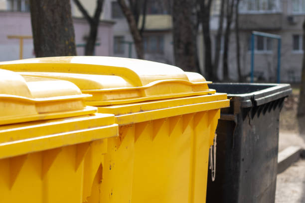 istock A yellow waste container is placed beside a black waste containment unit 2196587675