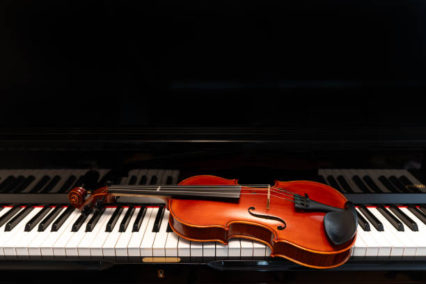 istock Violin on top of piano keyboard background 2196593451