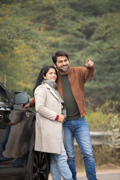 istock Man pointing and woman looking away while standing by car 2196596731