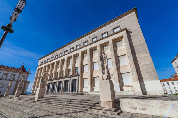 istock A modern building with large letters on the facade stands on a patterned stone plaza, featuring statues and a clear blue sky in the background. 2196597370