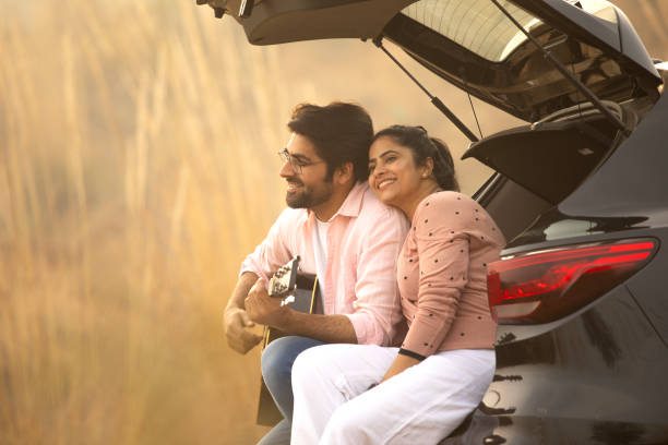 istock Young couple enjoying music while relaxing in car trunk 2196598873
