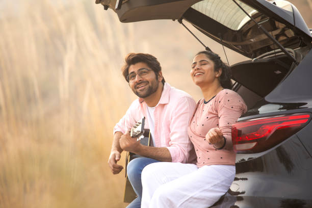 istock Young couple enjoying music while relaxing in car trunk 2196598905