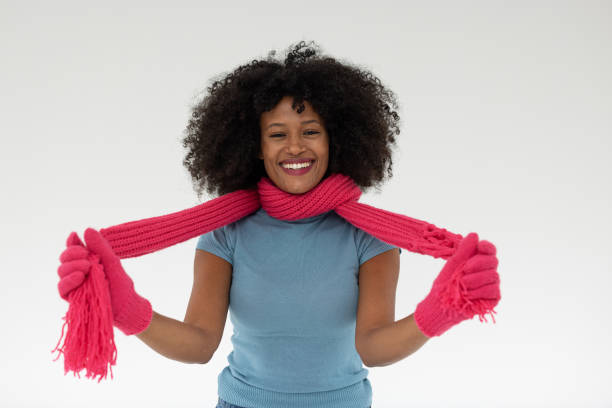 A cheerful woman showcasing a pink headscarf with a joyful expression, dressed in a stylish blue top, radiating positive vibes and creativity.