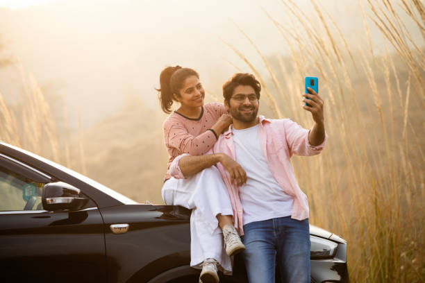 istock Young couple taking selfie over mobile phone by car 2196603984