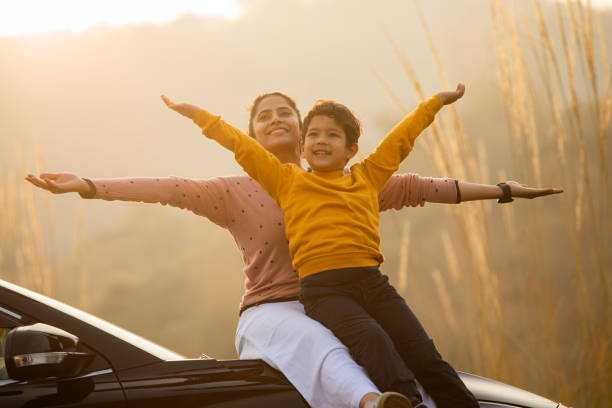 istock Mother and son with arms outstretched sitting on car 2196604717