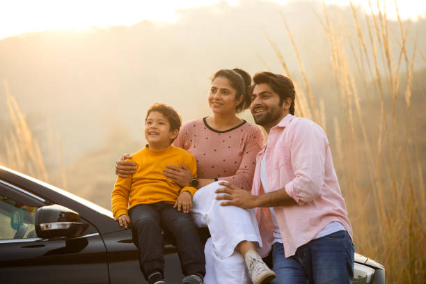 istock Young parents and son sitting on car hood while enjoying weekend amidst nature 2196605729
