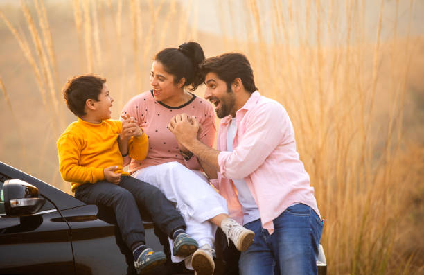 istock Young parents and son sitting on car hood while enjoying weekend amidst nature 2196605816