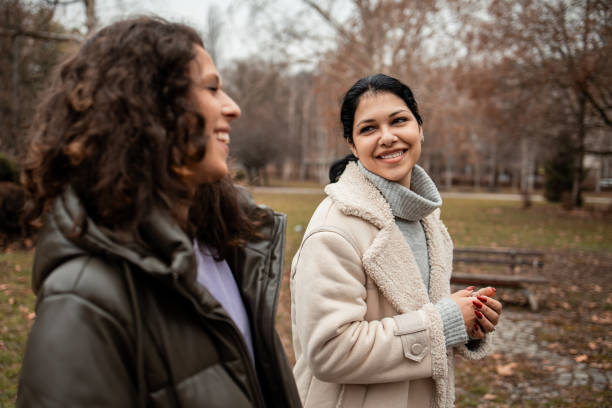 istock Two girls walking and talking in the park 2196611081