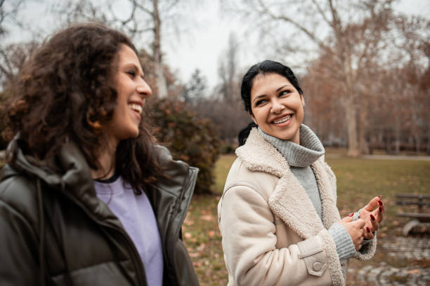istock Two girls walking and talking in the park 2196611085