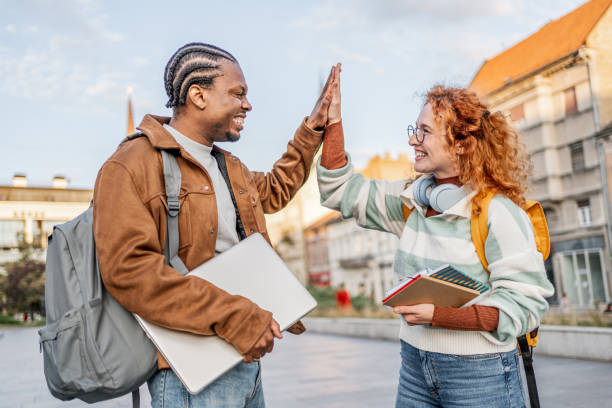 Two young college students cheerfully high-fiving on campus