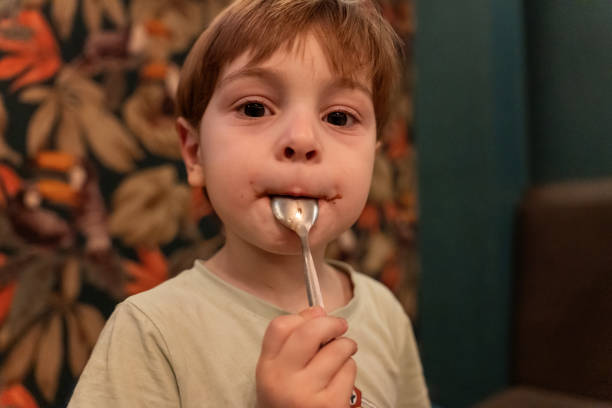 istock Young Child Enjoying Food with a Spoon in a Cozy Setting 2196613212