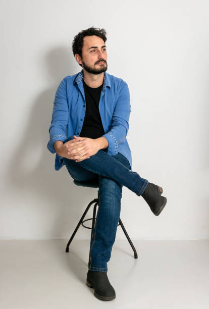 istock Man sitting on a chair and looking away in the studio 2196613403