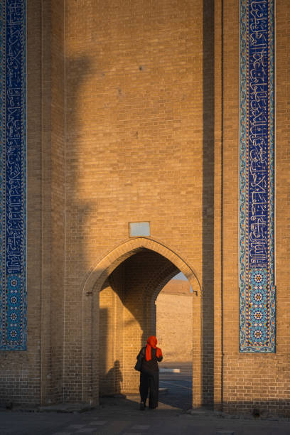 Woman walking through traditional iranian gate at sunset
