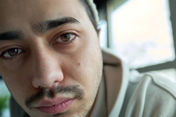 Close-up portrait of a sad young man looking at the camera with a thoughtful expression