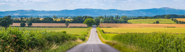 Long straight country road through fields to hills panorama Mlaverns