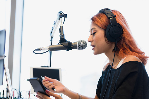 Podcaster Using A Microphone Young Woman Podcaster Using Microphone And Tablet Stock Photo ...