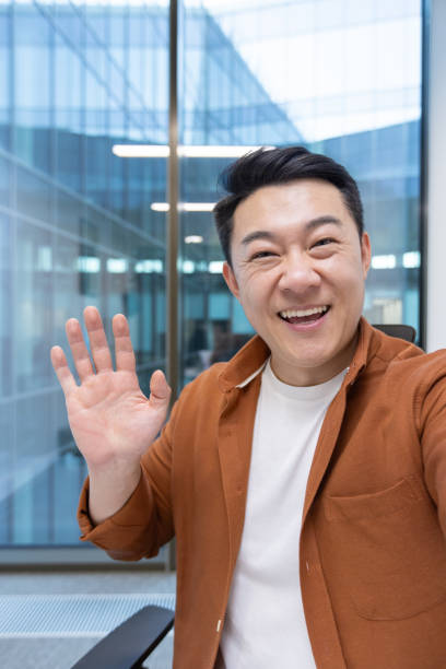 istock Video call, Asian man looking into phone camera and talking to colleagues using smartphone app. Businessman at workplace inside office 2196622331