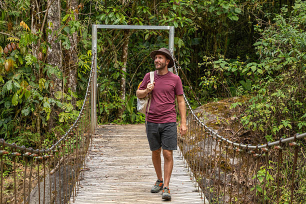 istock Man Walking on Jungle Suspension Bridge with Backpack 2196629632