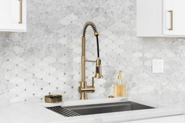 A gold faucet detail in a white kitchen.