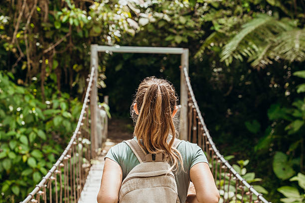 istock Woman Hiking Across Jungle Bridge with Backpack 2196629888