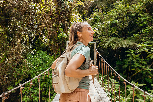 istock Woman Hiking Across Jungle Bridge with Backpack 2196629898