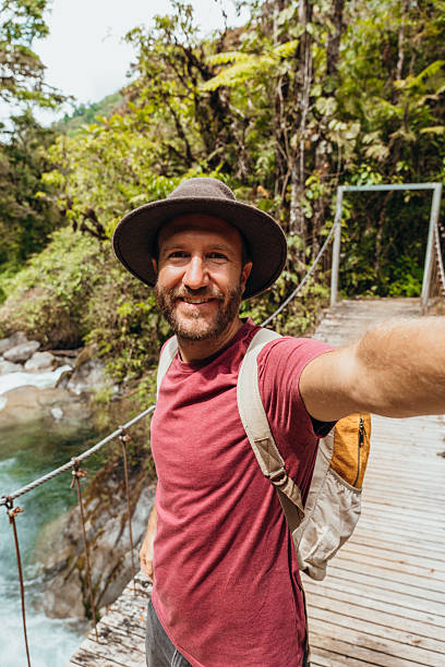 istock Man Taking Selfie on Scenic Jungle Bridge 2196629976