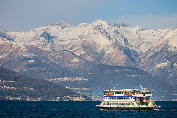 A ferry boat that just left from Bellagio on the Como Lake with the snow covered Alps in the background, Italy