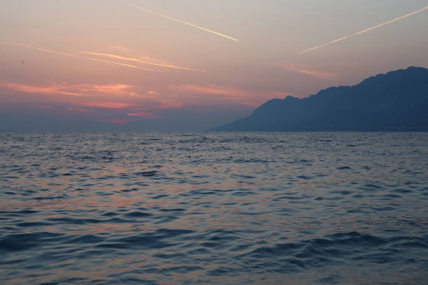 Picturesque clouds at sunset over the sea on a summer evening, silhouette of mountains on the horizon, Brela, Croatia