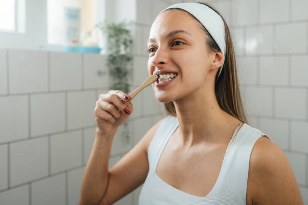 istock Smiling young woman brushing teeth with toothbrush in a bright bathroom 2196632924