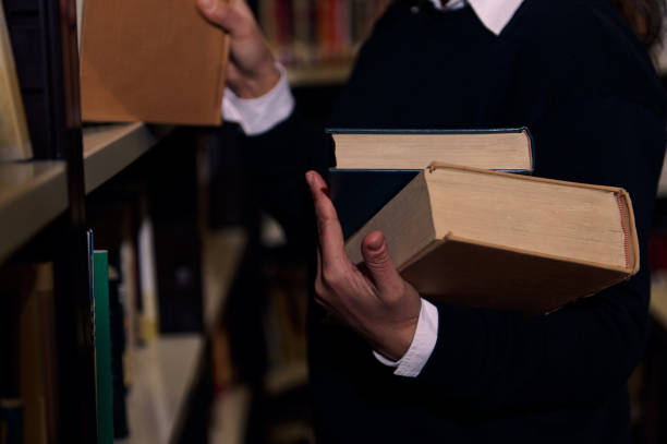 istock Person selecting books from a library shelf for reading and research 2196634708