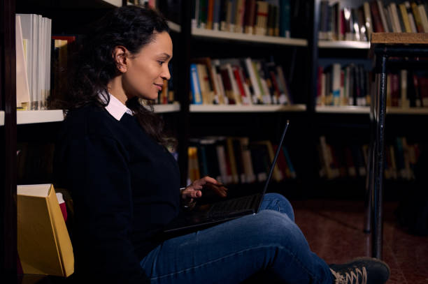 istock Woman studying in a library using a laptop on the floor 2196634714