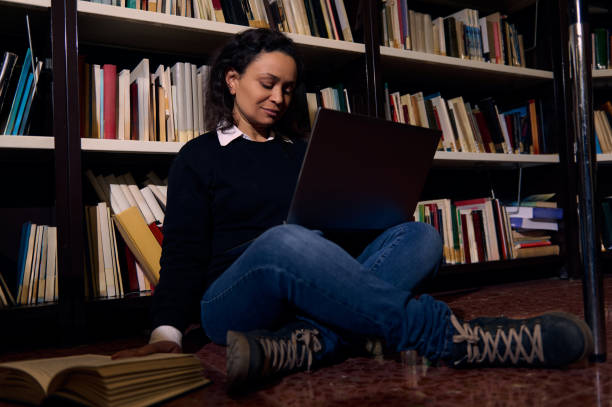 istock Woman sitting in library using a laptop for research and learning 2196634728