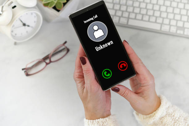 istock Hand holding cellphone with incoming call from Unknown Caller - fraud scam phishing call spoofing 2196637345