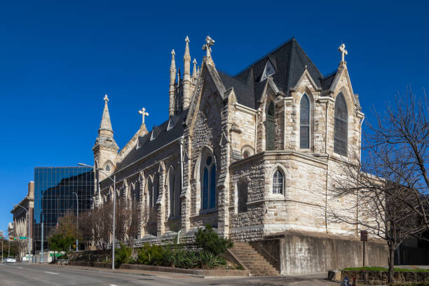 A striking view of Saint Mary's Cathedral in downtown Austin, Texas. Built in the Gothic Revival style, this historic church features intricate stonework, pointed arch windows, and towering spires adorned with crosses. Established in the 19th century, the cathedral remains a significant landmark and place of worship in the city.