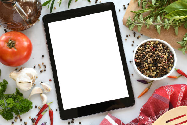 istock Tablet computer with mock up white screen in kitchen with food flat lay background. 2196637605
